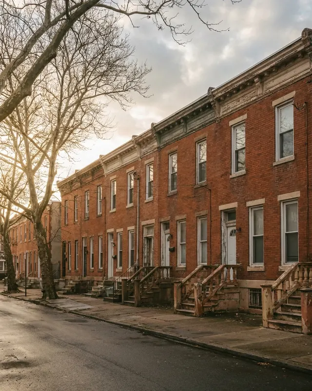 A row of brick houses with front stoops on a residential street at golden hour